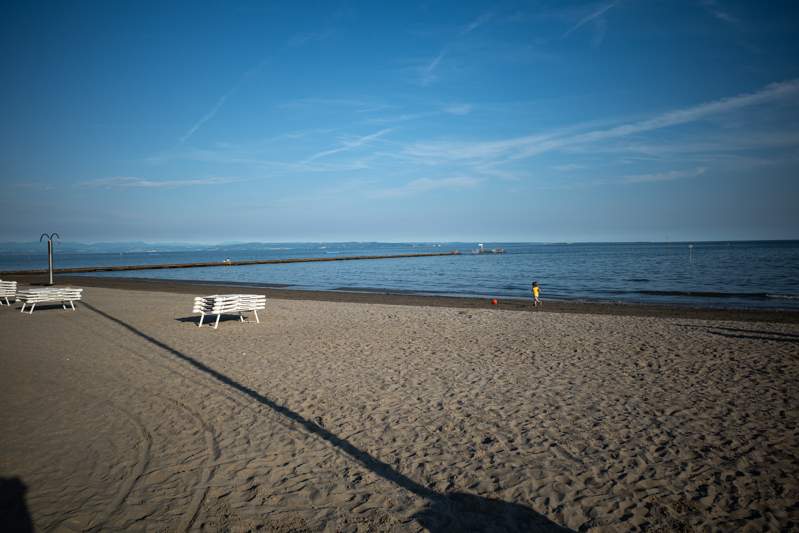 Abends am Strand: die Liegen zusammengeklappt, ein Kind läuft ins Wasser
